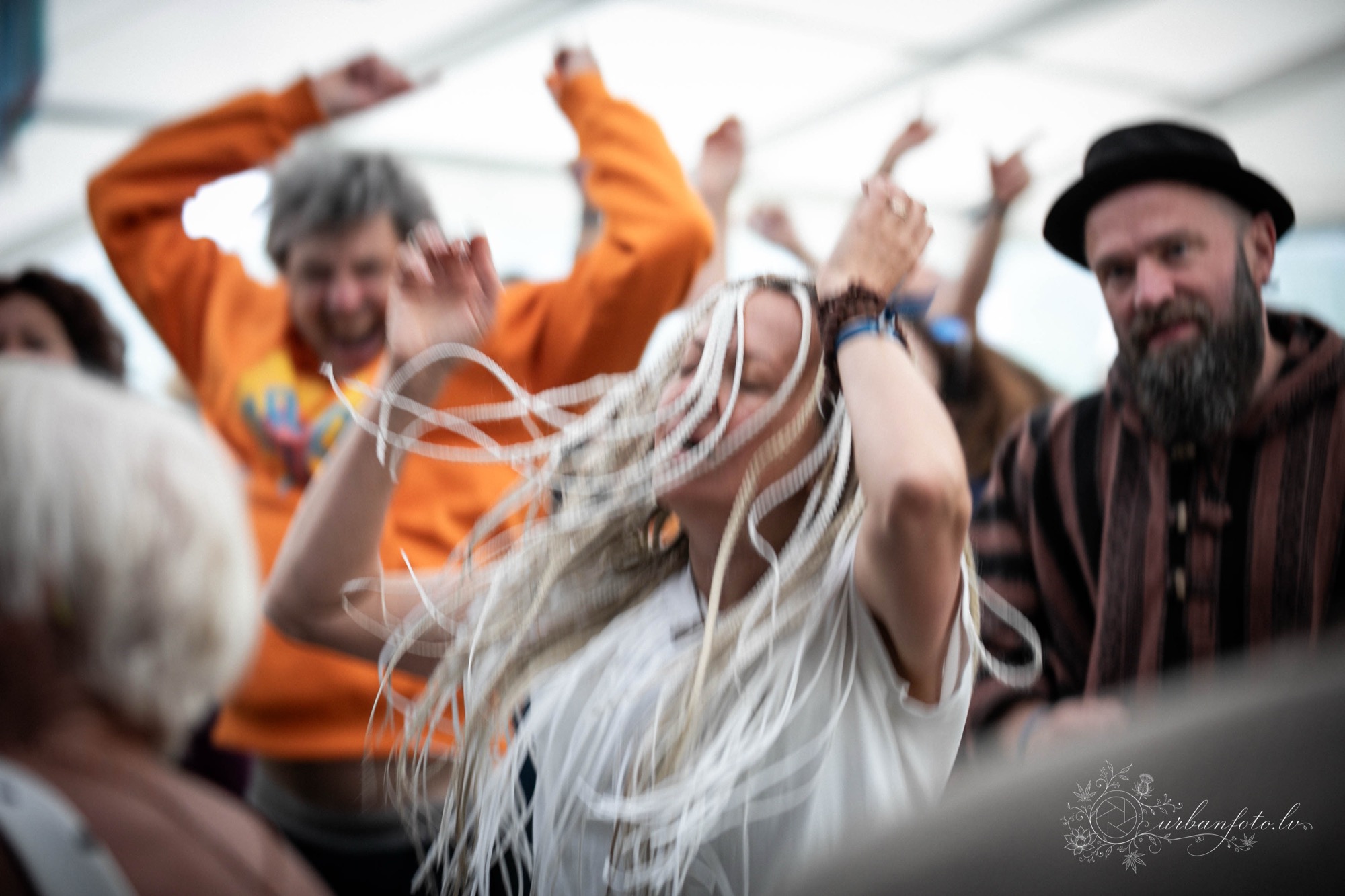 A dancer with flowing white braids throws herself into the rhythm, surrounded by fellow festival-goers celebrating together at BŪTĪBA Festival 2026. 💃🎶