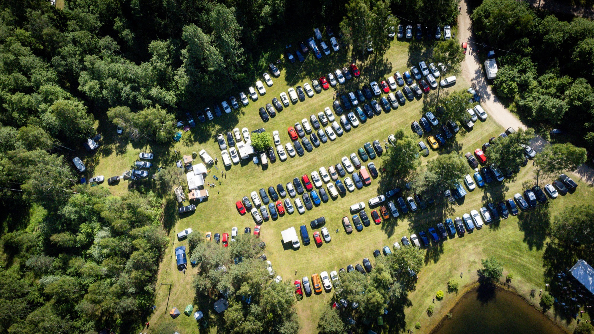Aerial view of the BŪTĪBA Festival 2026 parking area surrounded by forest and green fields