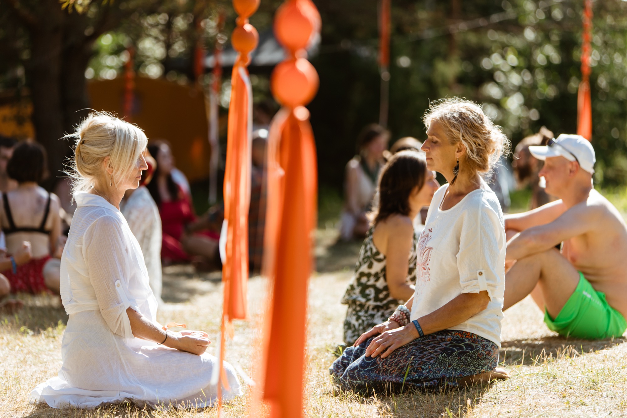 Two festival participants sitting opposite each other in a quiet outdoor conversation area surrounded by trees at BŪTĪBA Festival 2026