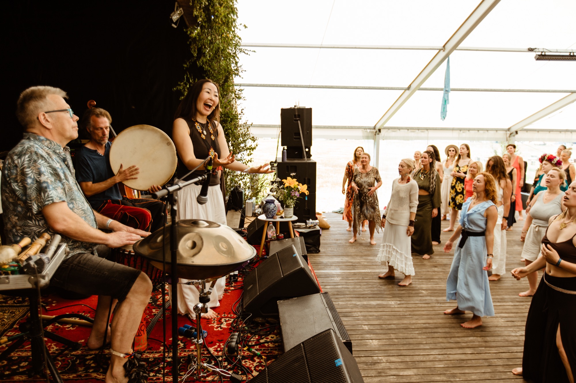 Musicians playing percussion instruments as a group of participants gather for a live music, dance and singing session at BŪTĪBA Festival 2026