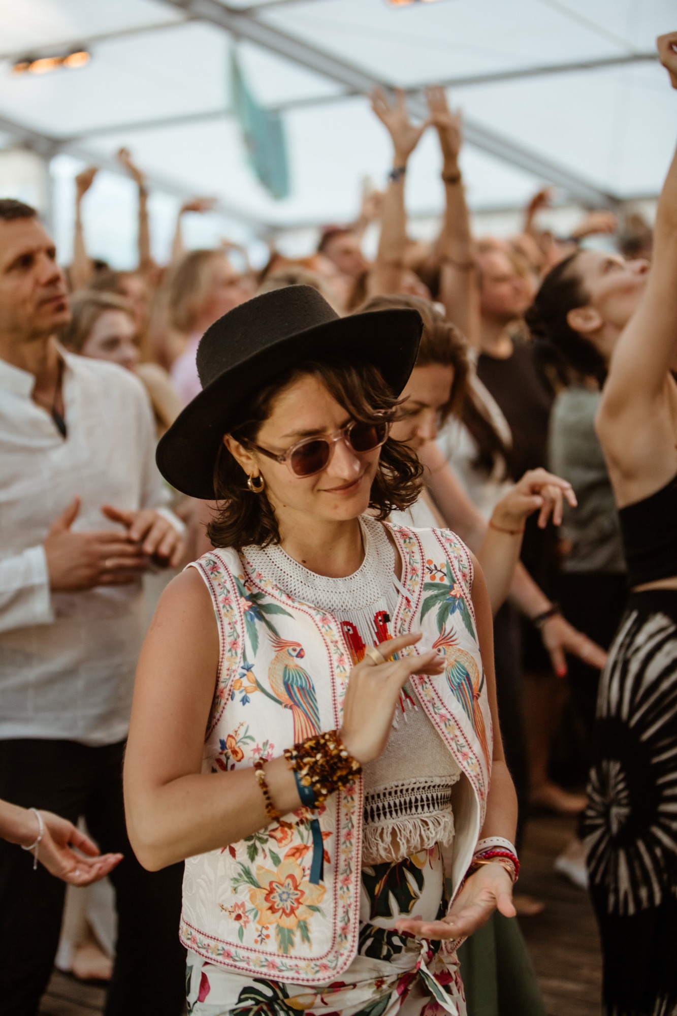 A festival-goer in a wide-brimmed hat and colourful embroidered top sways to the music at BŪTĪBA Festival.