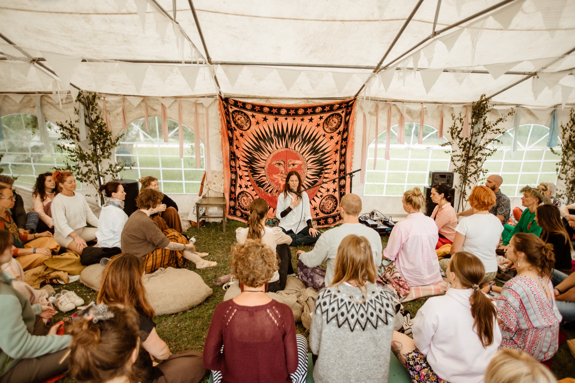 Workshop participants seated in a circle listening to a facilitator inside the BŪTĪBA Festival 2026 tent