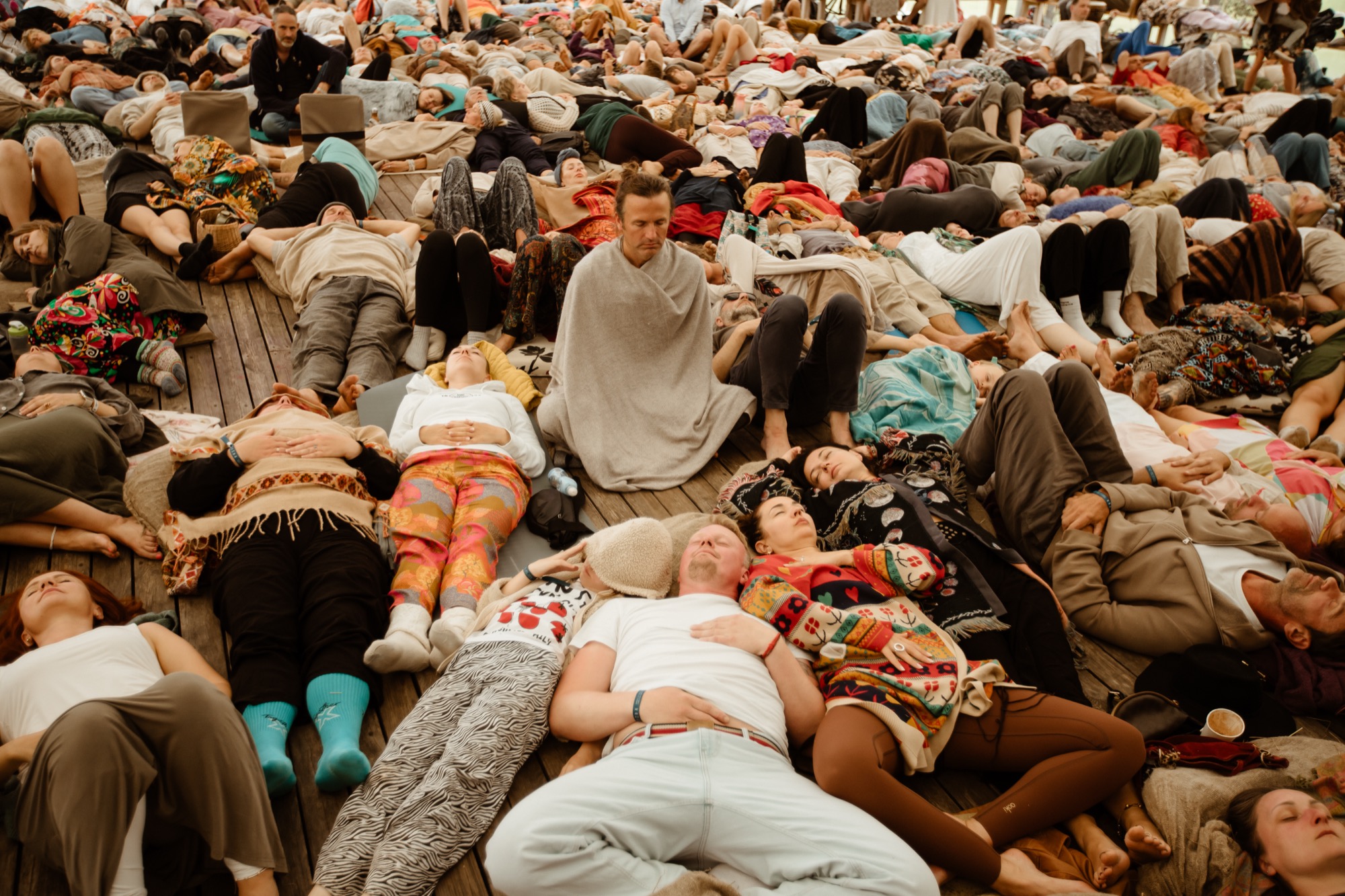 Festival participants lying on the floor during a relaxation and meditation session at BŪTĪBA Festival 2026