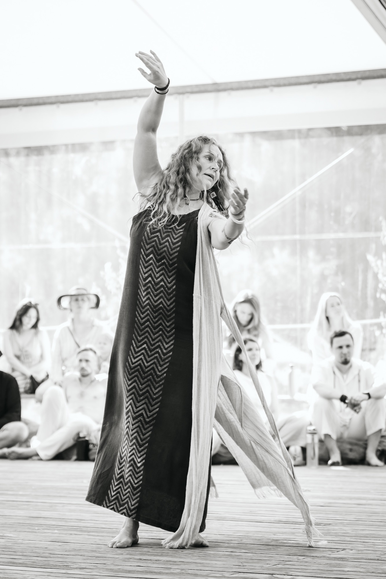 Woman leading a movement workshop at BŪTĪBA Festival 2026, raising her arms as participants watch