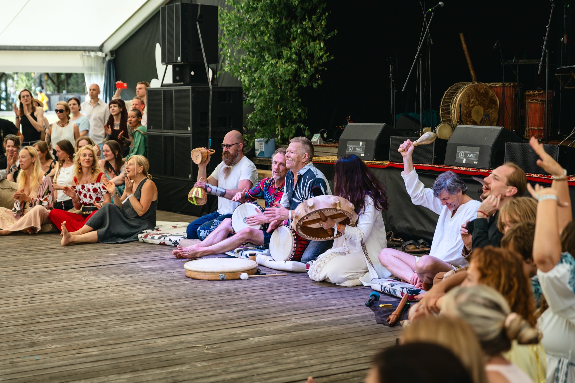 Festival participants and teachers seated in a circle playing shamanic drums together at BŪTĪBA Festival 2026