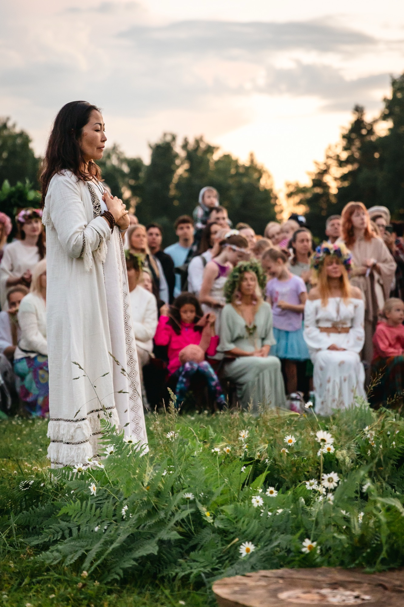 Woman standing with eyes closed and hands over her heart during a sunset ceremony at BŪTĪBA Festival 2026