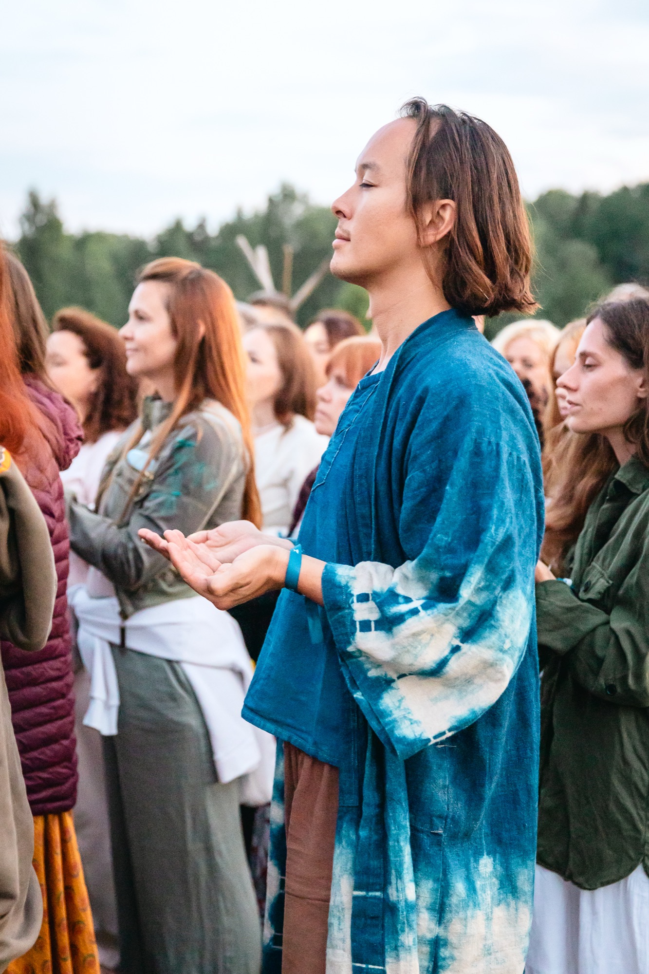 Festival participants taking part in a fire ceremony at BŪTĪBA Festival 2026, with open palms and eyes closed