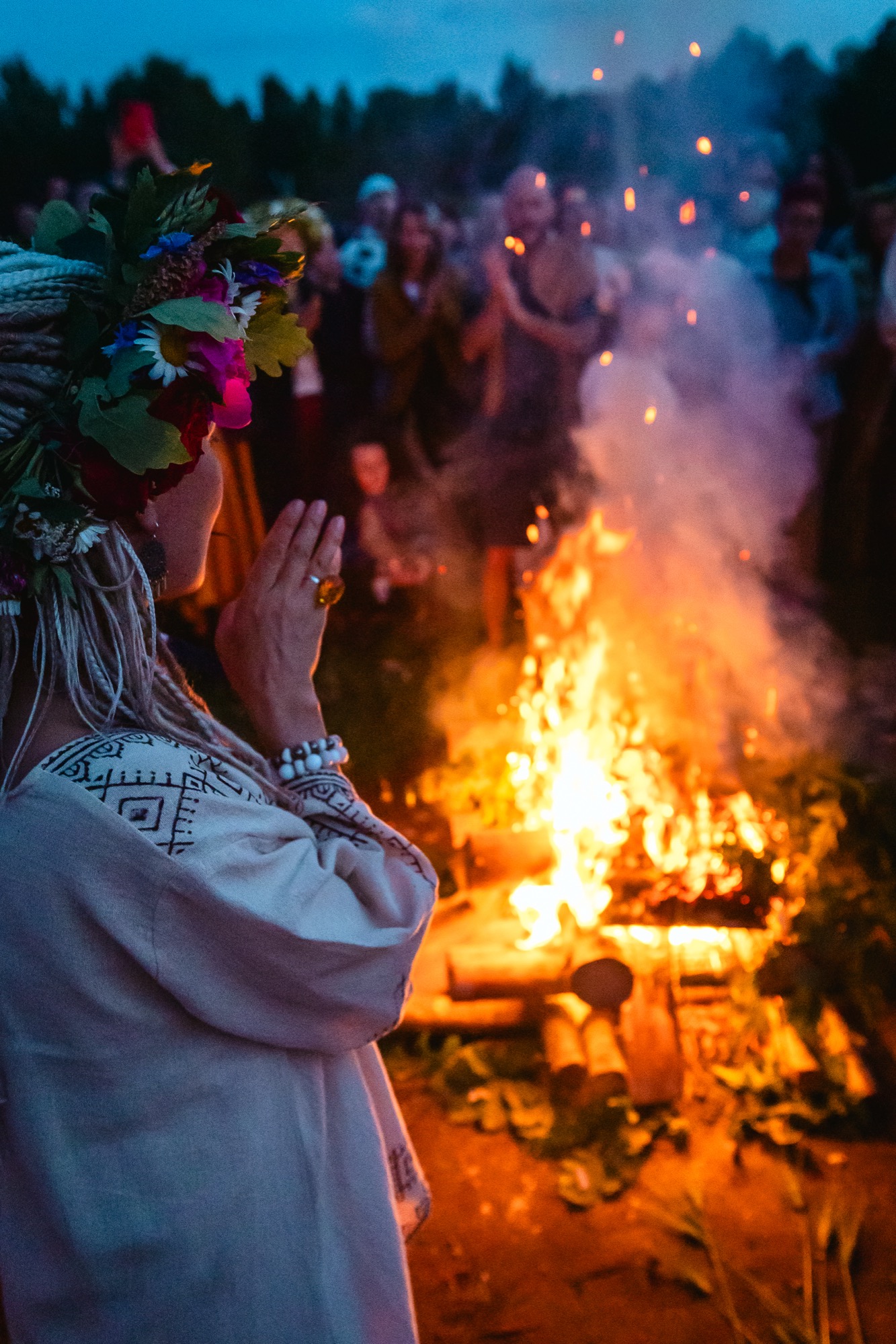 Festival participant sitting quietly beside a glowing bonfire during BŪTĪBA Festival 2026