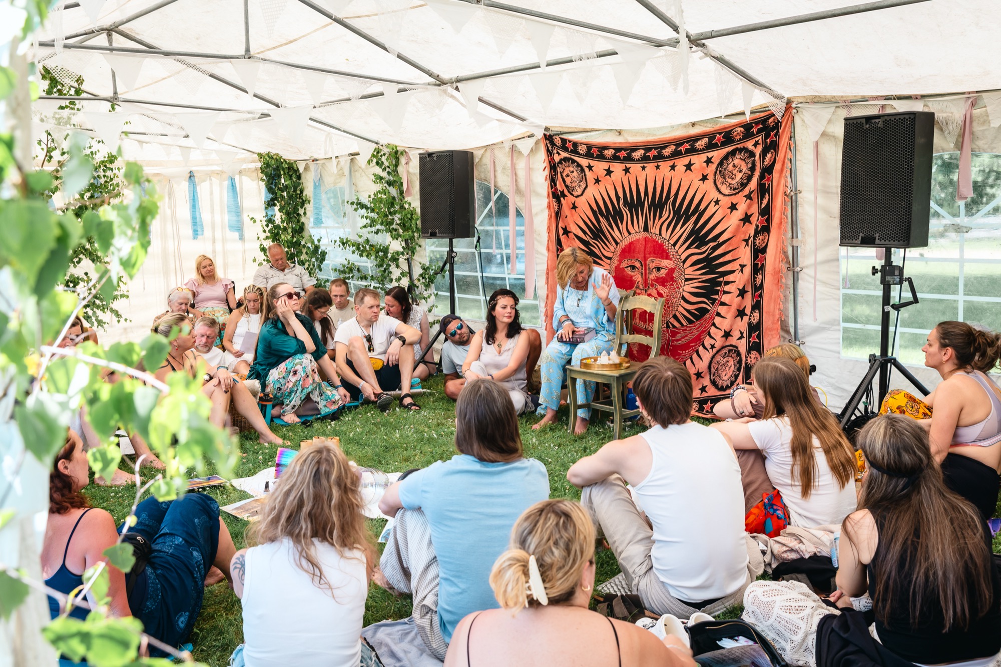 Participants seated in a circle for a guided group workshop beneath a sun-patterned tapestry at BŪTĪBA Festival 2026
