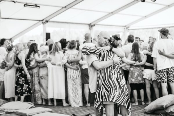 Participants embracing during a group connection workshop at BŪTĪBA Festival 2026, captured in black and white
