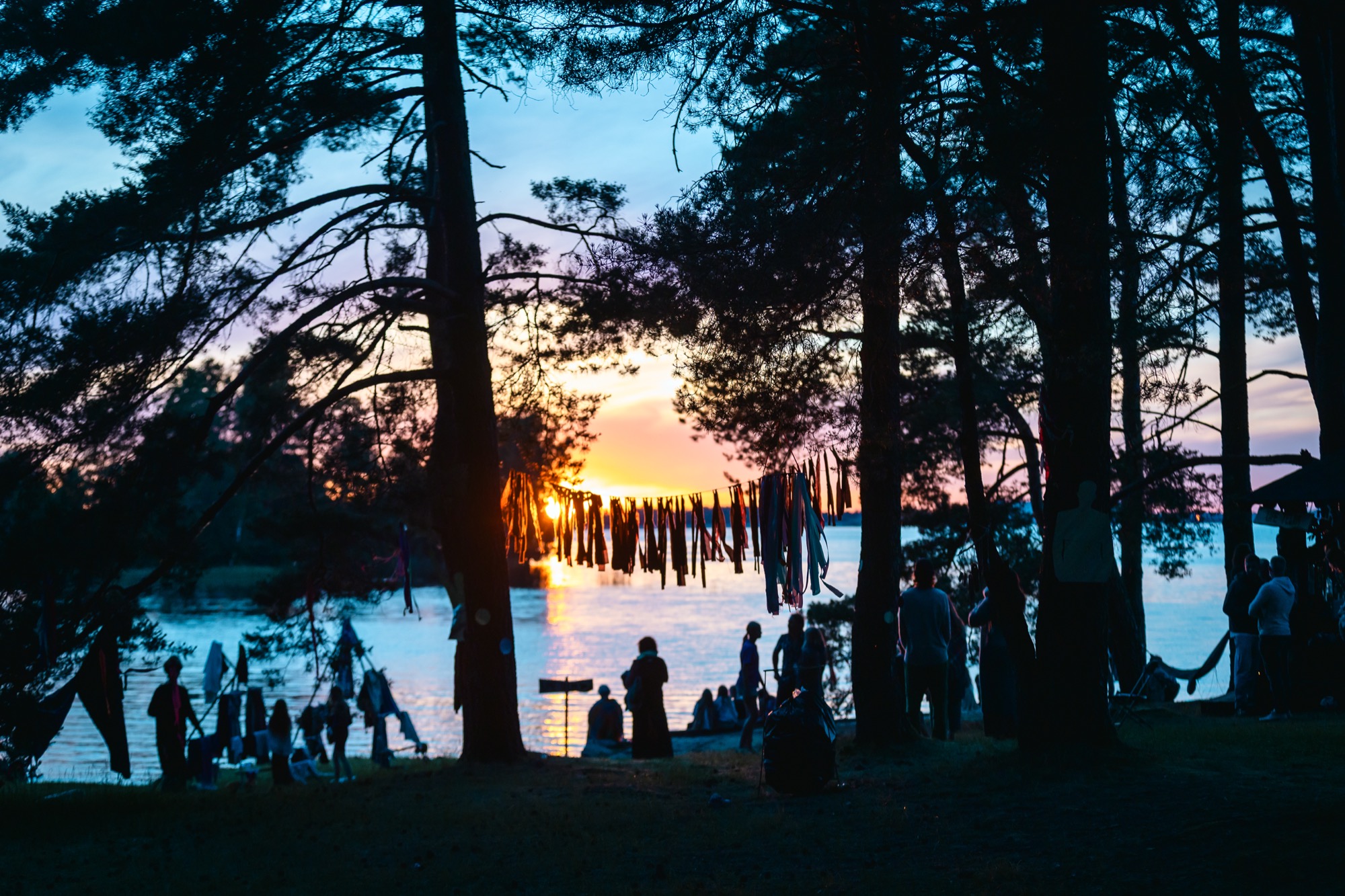 Cilvēki pulcējas pie Daugavas krasta, lai vērotu saules lēktu vasaras saulgriežu svinībās BŪTĪBA festivālā.