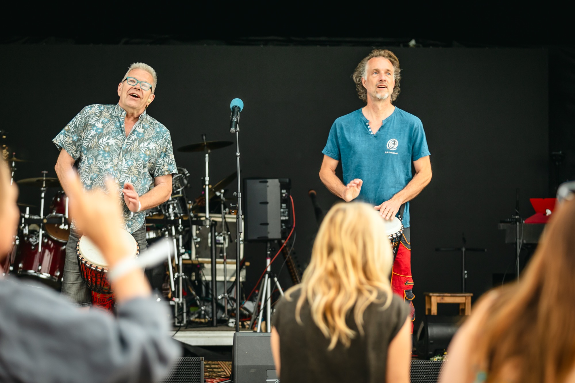 Rishi and Shakya leading a live drumming workshop on stage at BŪTĪBA Festival 2026, with participants joining in