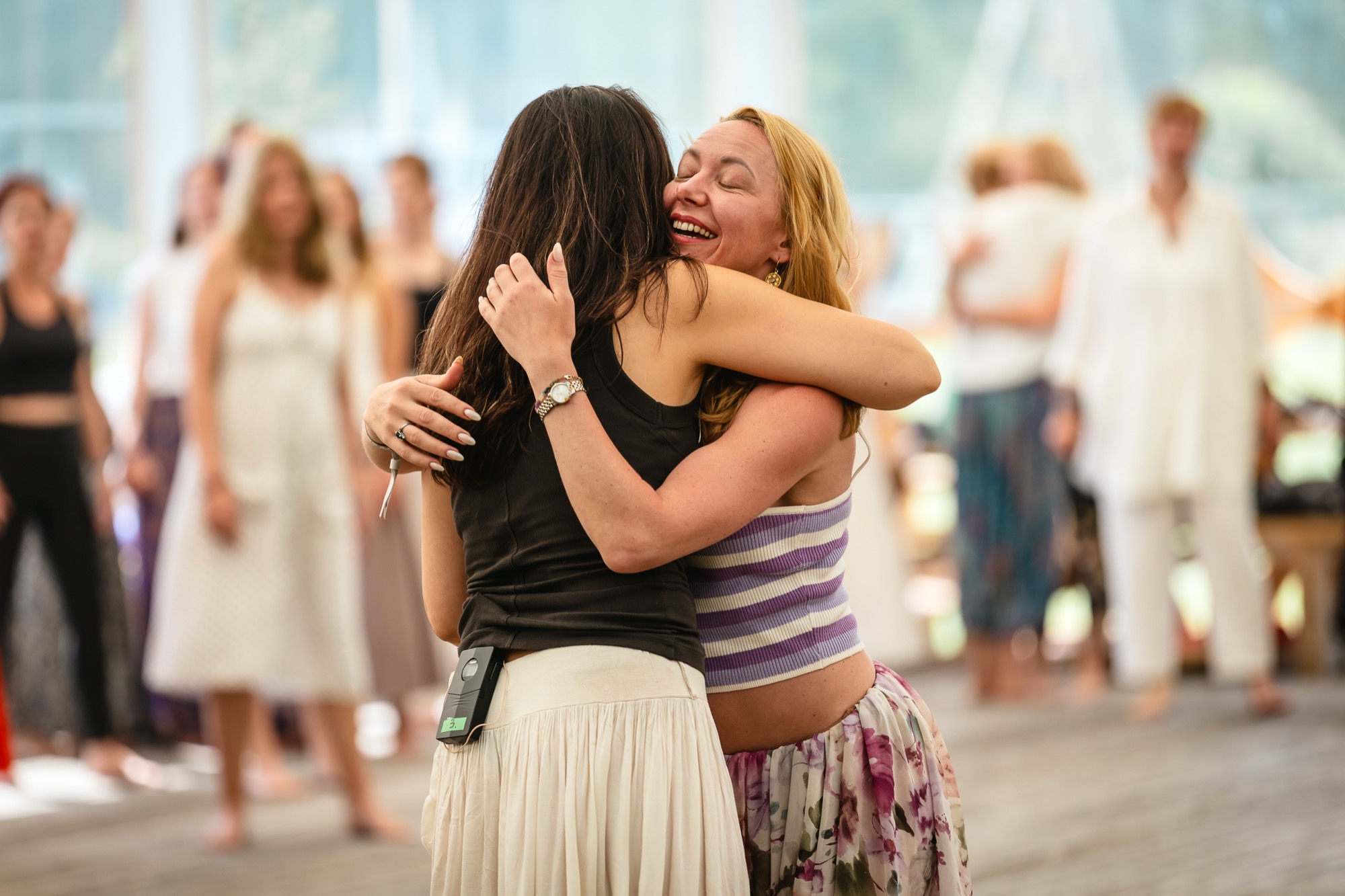 Two women embracing warmly during a connection workshop at BŪTĪBA Festival 2026