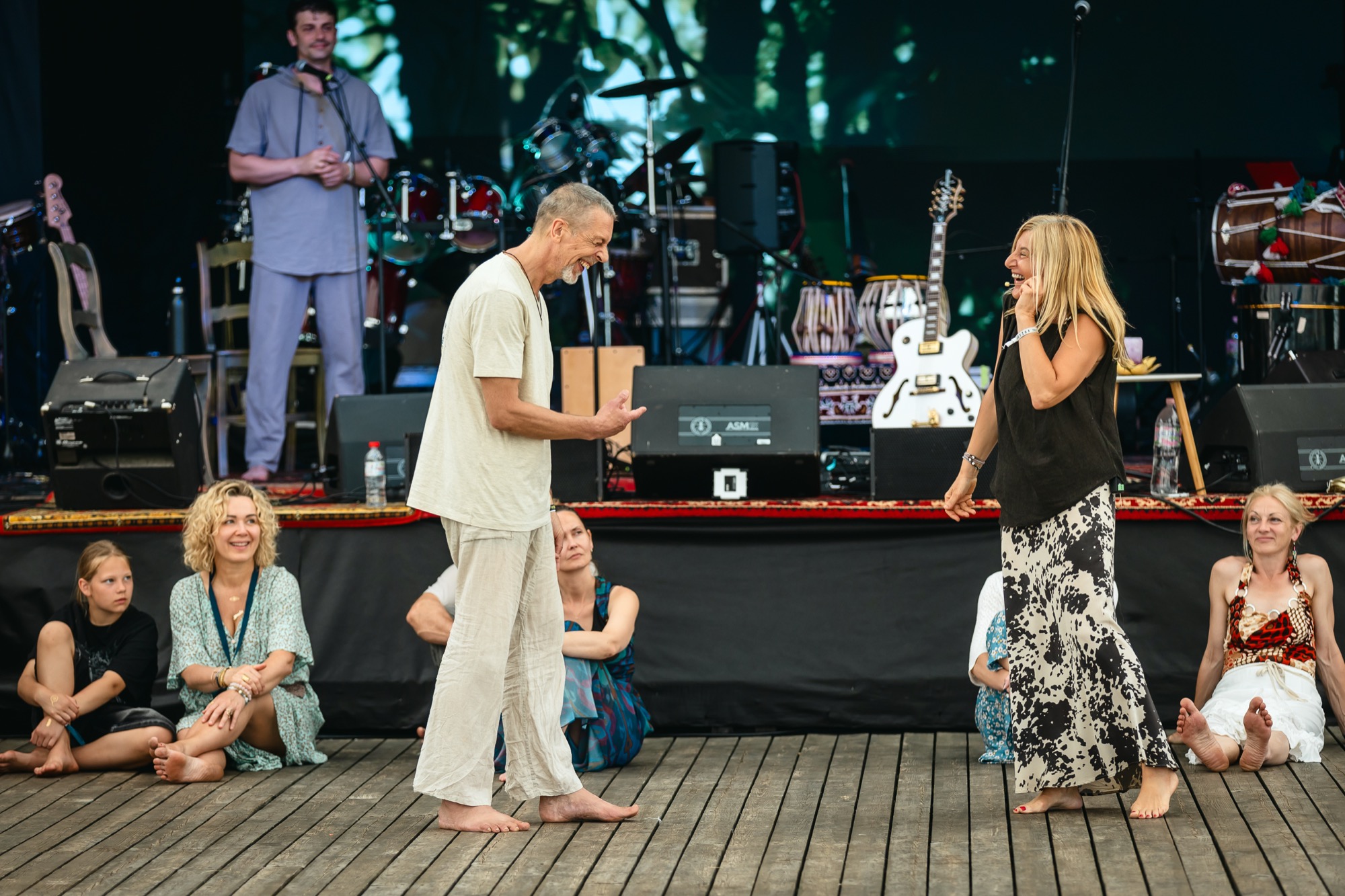 BUTIBA Festival 2026 facilitators Abhika and Juris Grave sharing a joyful moment during a tantra workshop on stage, surrounded by instruments and festival energy