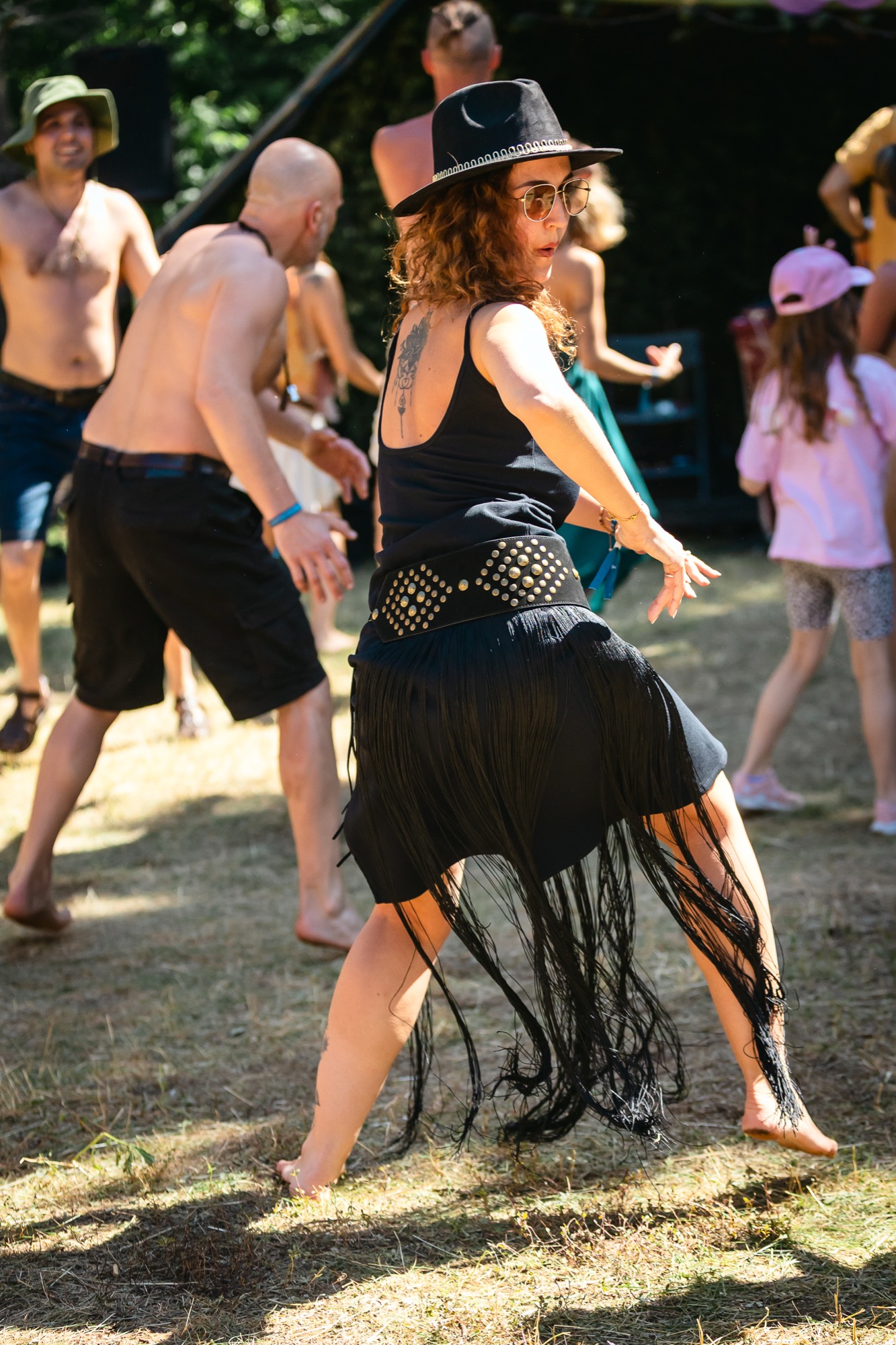 Woman in a black hat dancing barefoot outdoors at BUTIBA Festival 2026