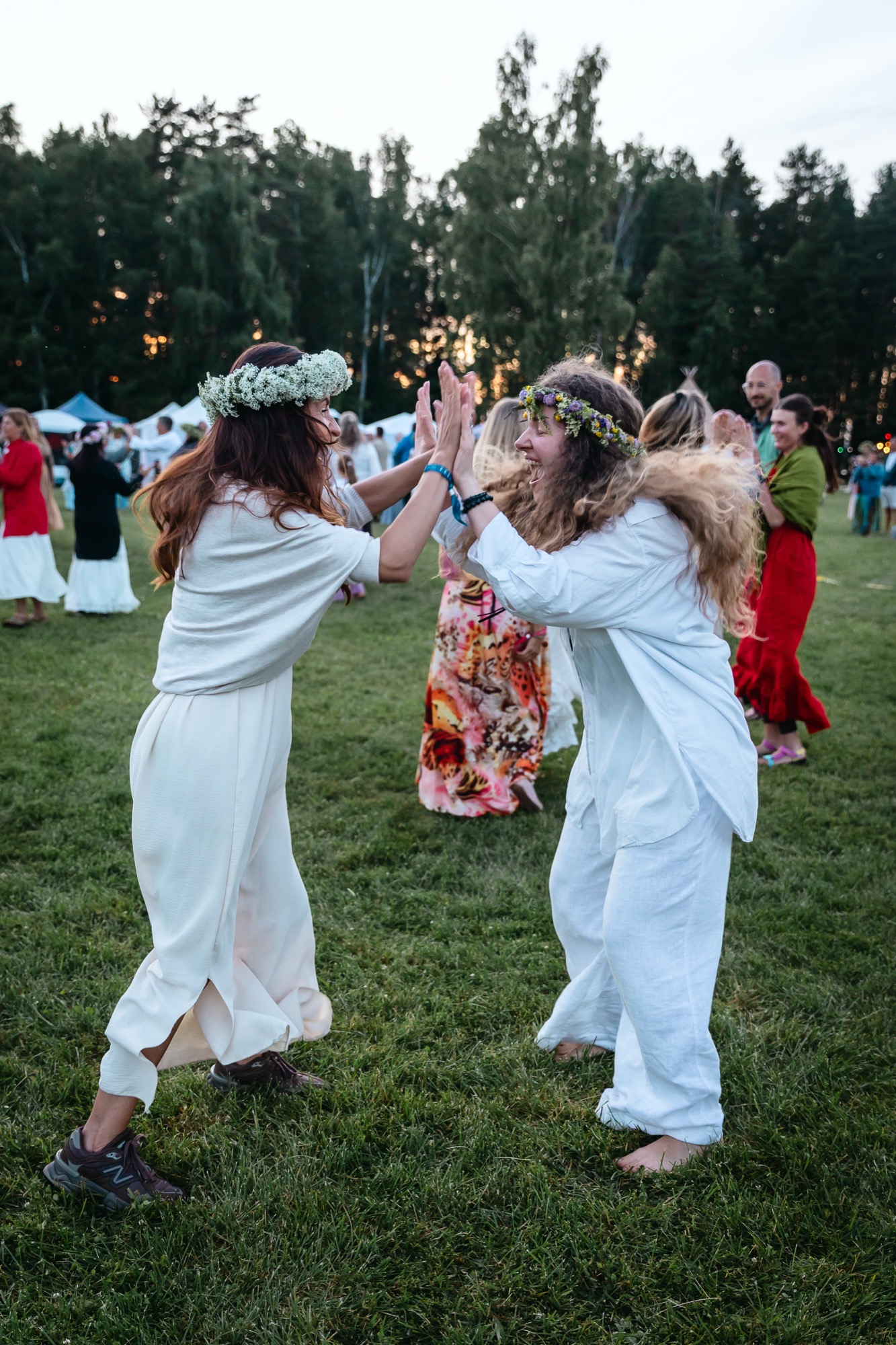 Festival participants dancing latvian folk fun dance on the grass at BŪTĪBA Festival 2026 at sunset