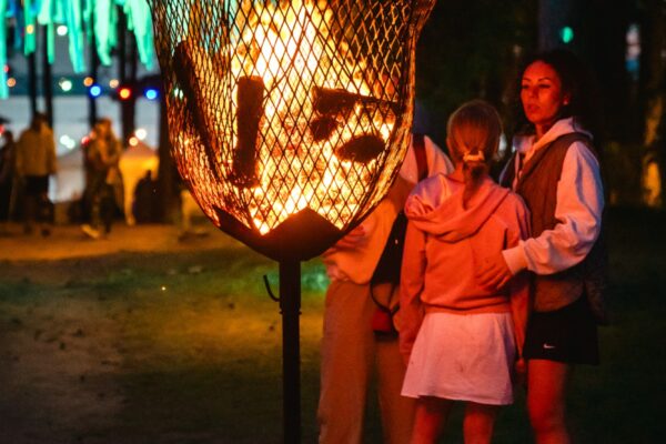 Ģimene sildās pie uguns laternas BŪTĪBA festivāla vakara noskaņās, baudot vasaras saulgriežu kopābūšanu.