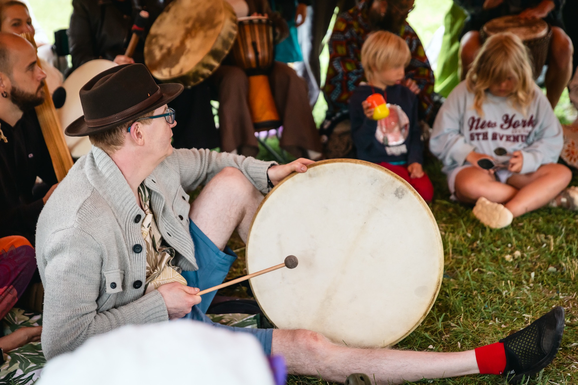 Participants playing large frame drums together with children during a family music workshop at BŪTĪBA Festival 2026
