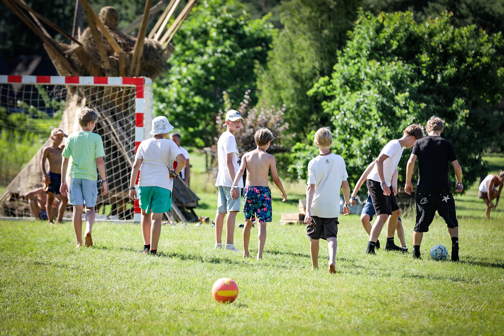 Bērni spēlē futbolu zaļā pļavā BŪTĪBA festivālā 2026 — ģimenēm draudzīgā vasaras saulgriežu festivālā, kas svin latviešu Jāņu un Līgo tradīcijas