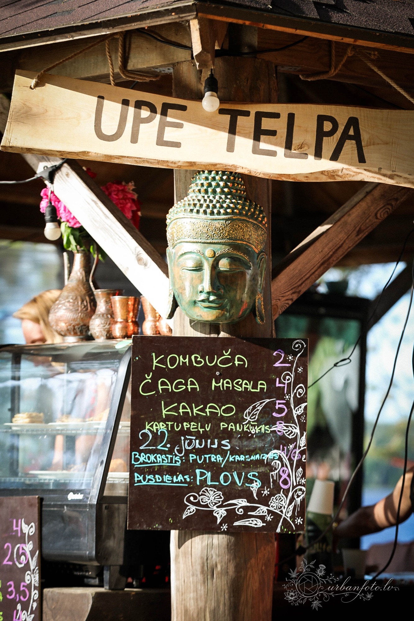 BŪTĪBA Festival 2026 drinks stall with a Buddha sculpture and a chalkboard menu