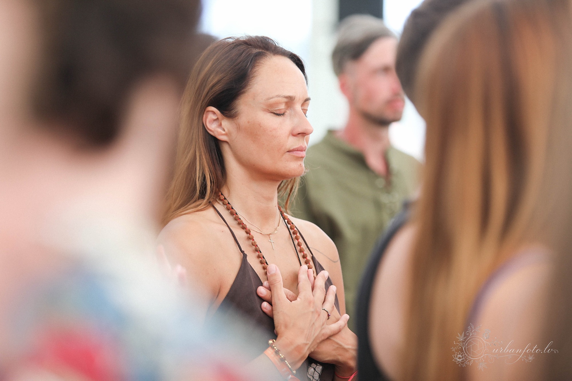Woman with eyes closed and hands resting on her chest during a mindfulness practice at BŪTĪBA Festival 2026