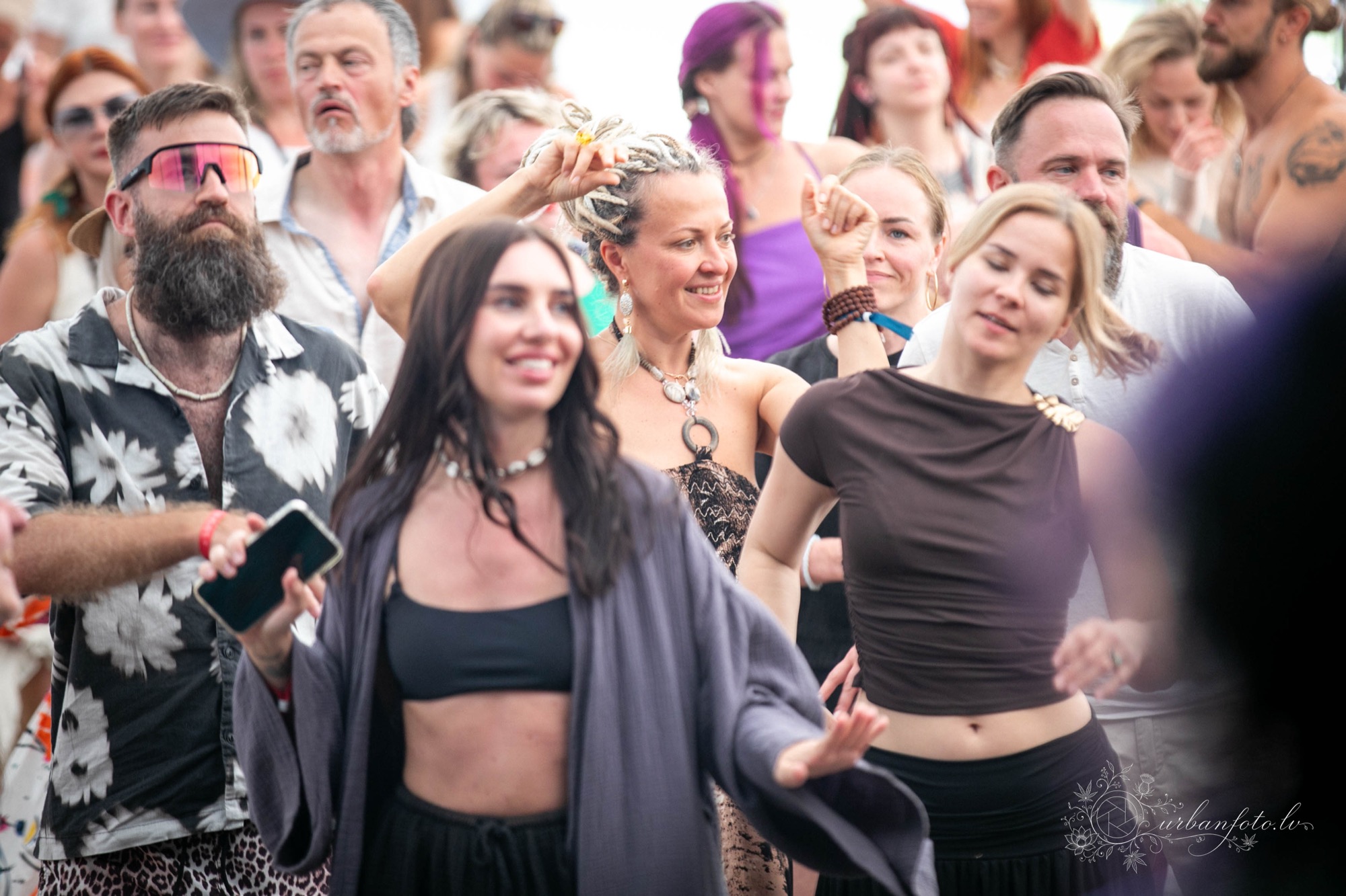 ALT teksts: Stilīgi ģērbušies BŪTĪBA festivāla apmeklētāji dejo un svin vasaras saulgriežus.