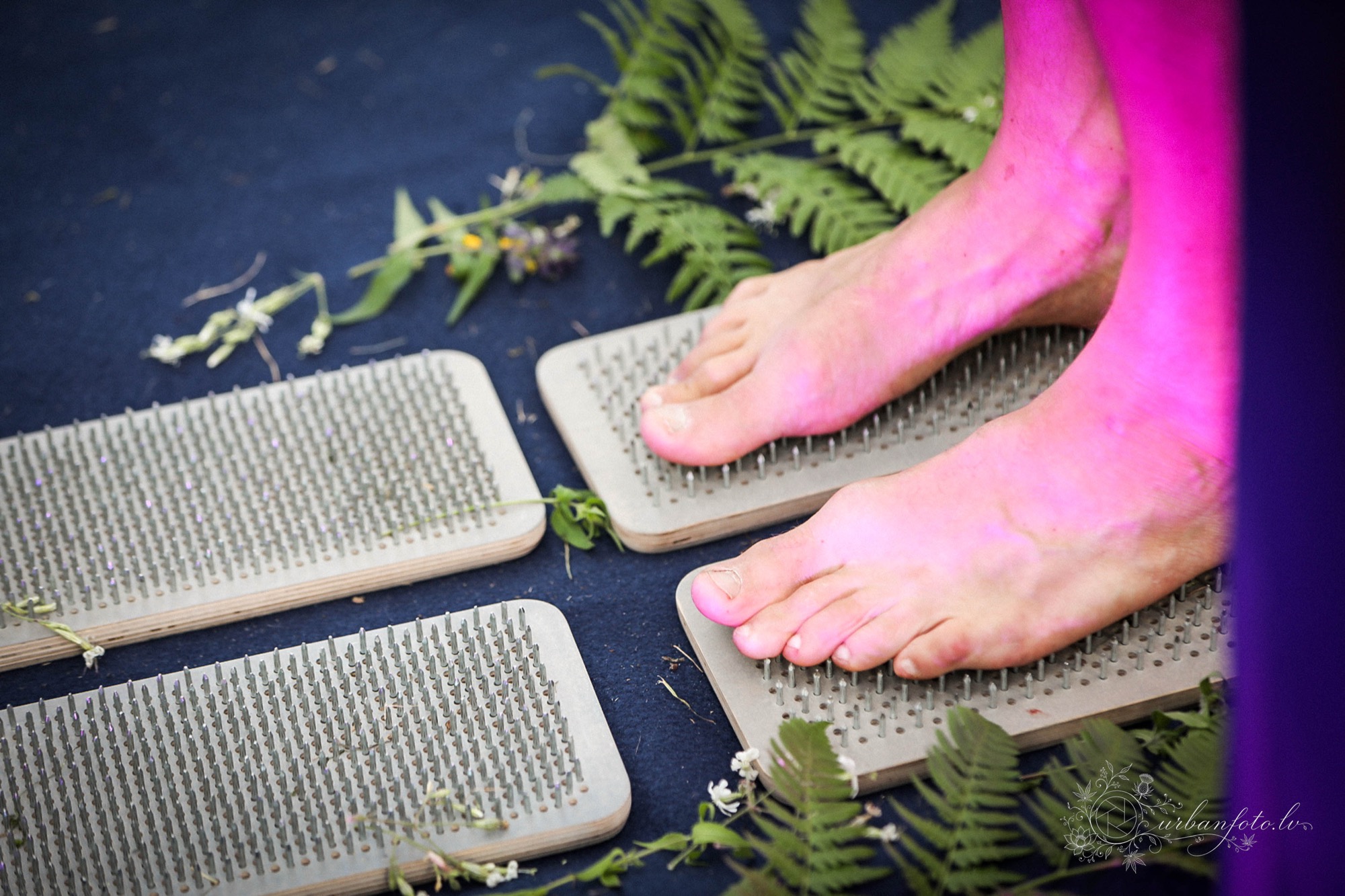 Festival participant standing barefoot on spiked acupressure boards during a wellness activity at BŪTĪBA Festival 2026